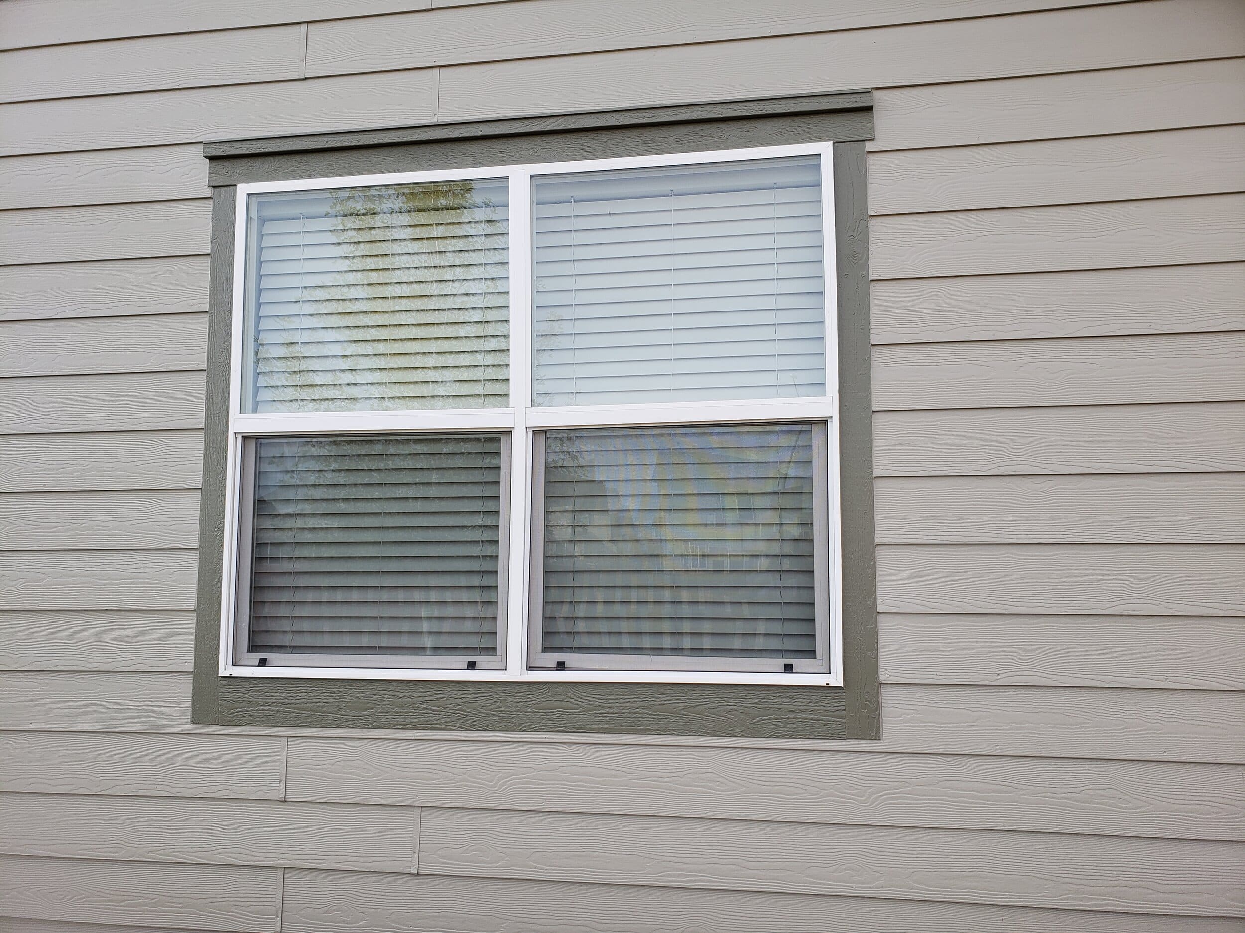 Outdoor view of a white window with dark trim on the side of a home