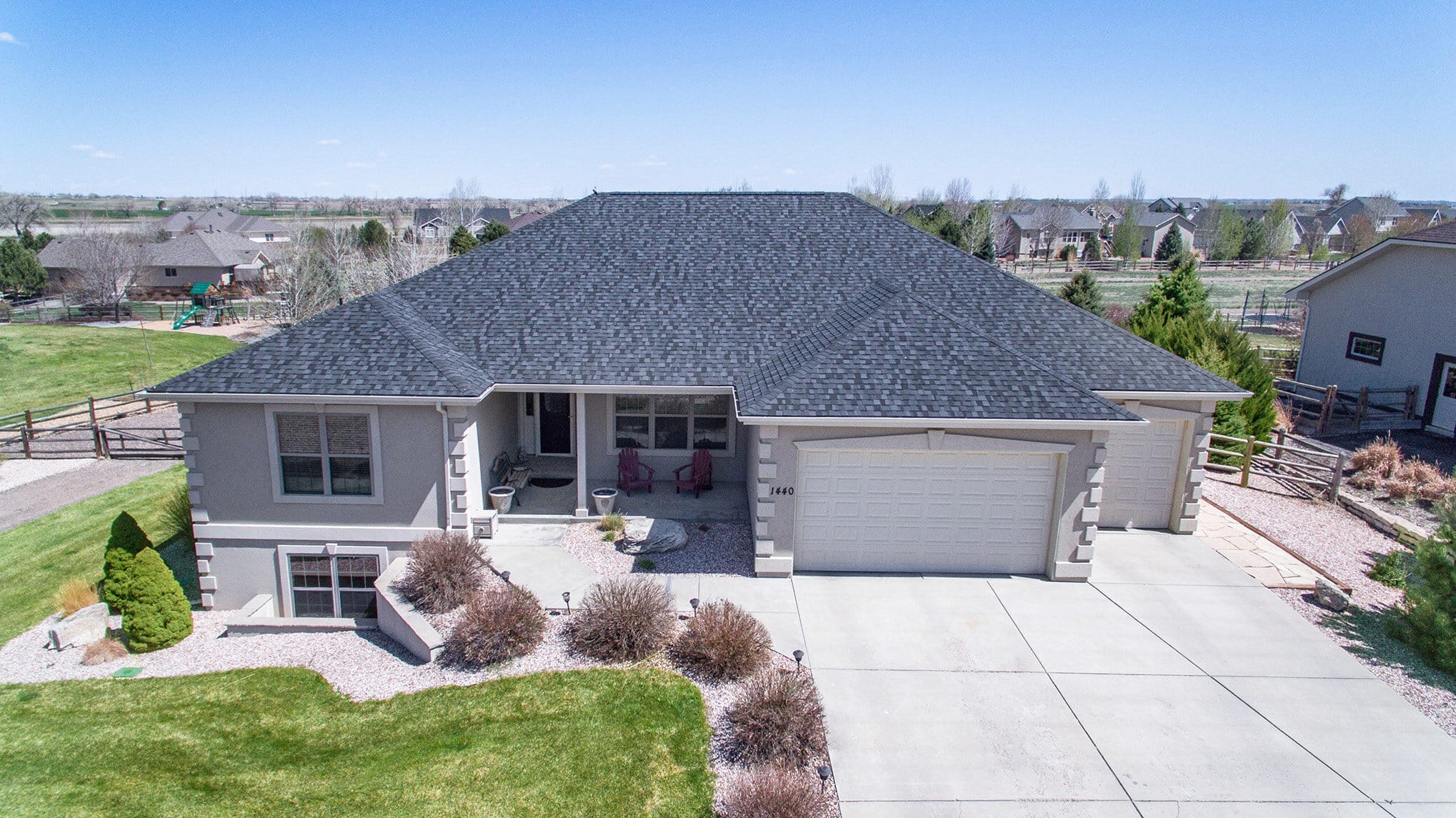 Aerial view of a home with a dark gray roof and white accents