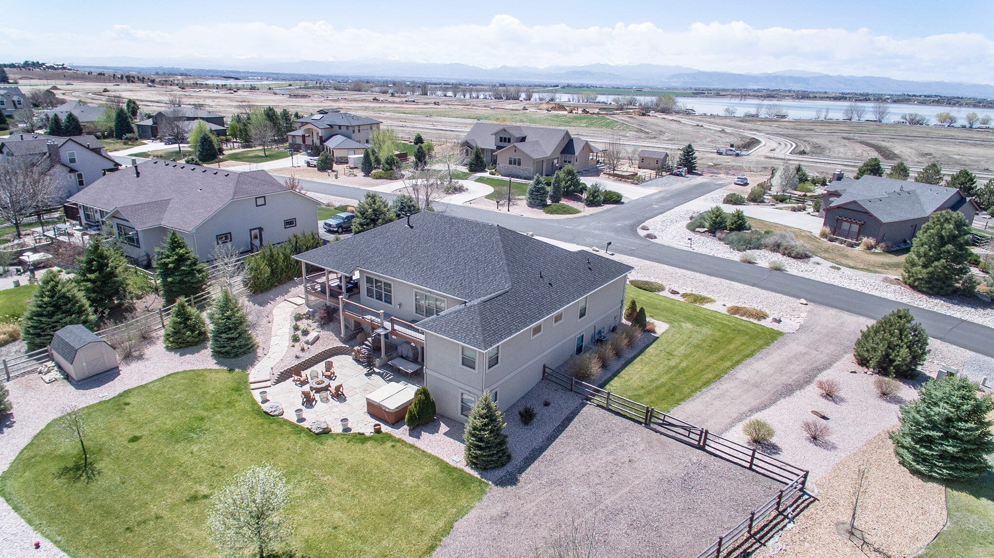 Aerial view of a large home in a neighborhood by a lake with mountains