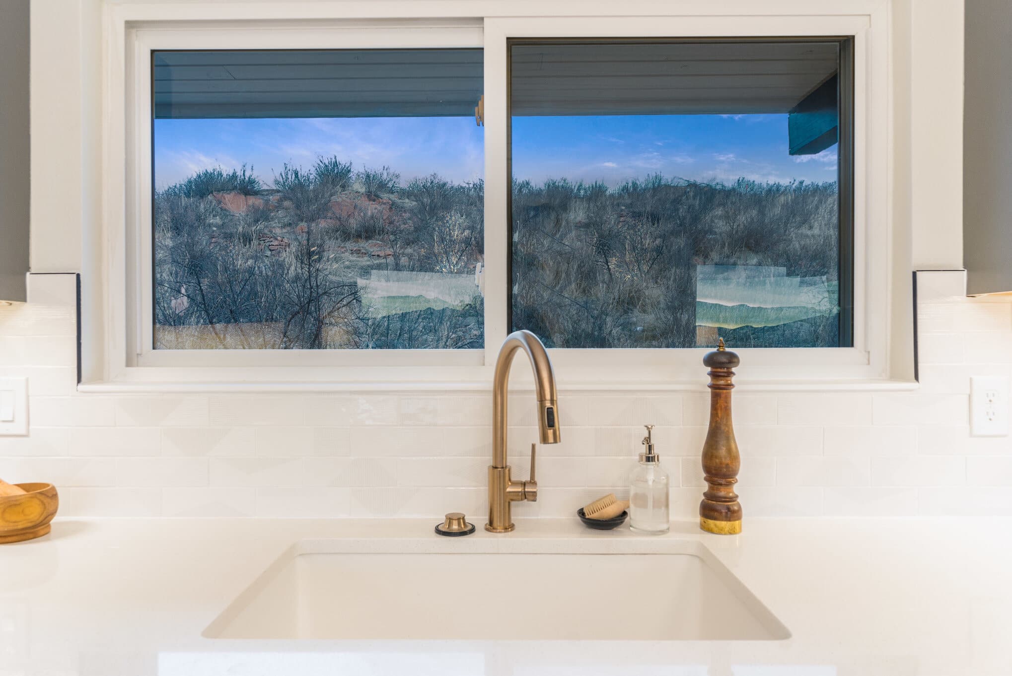 Oversized kitchen sink with window overlooking the mountains and gold faucet