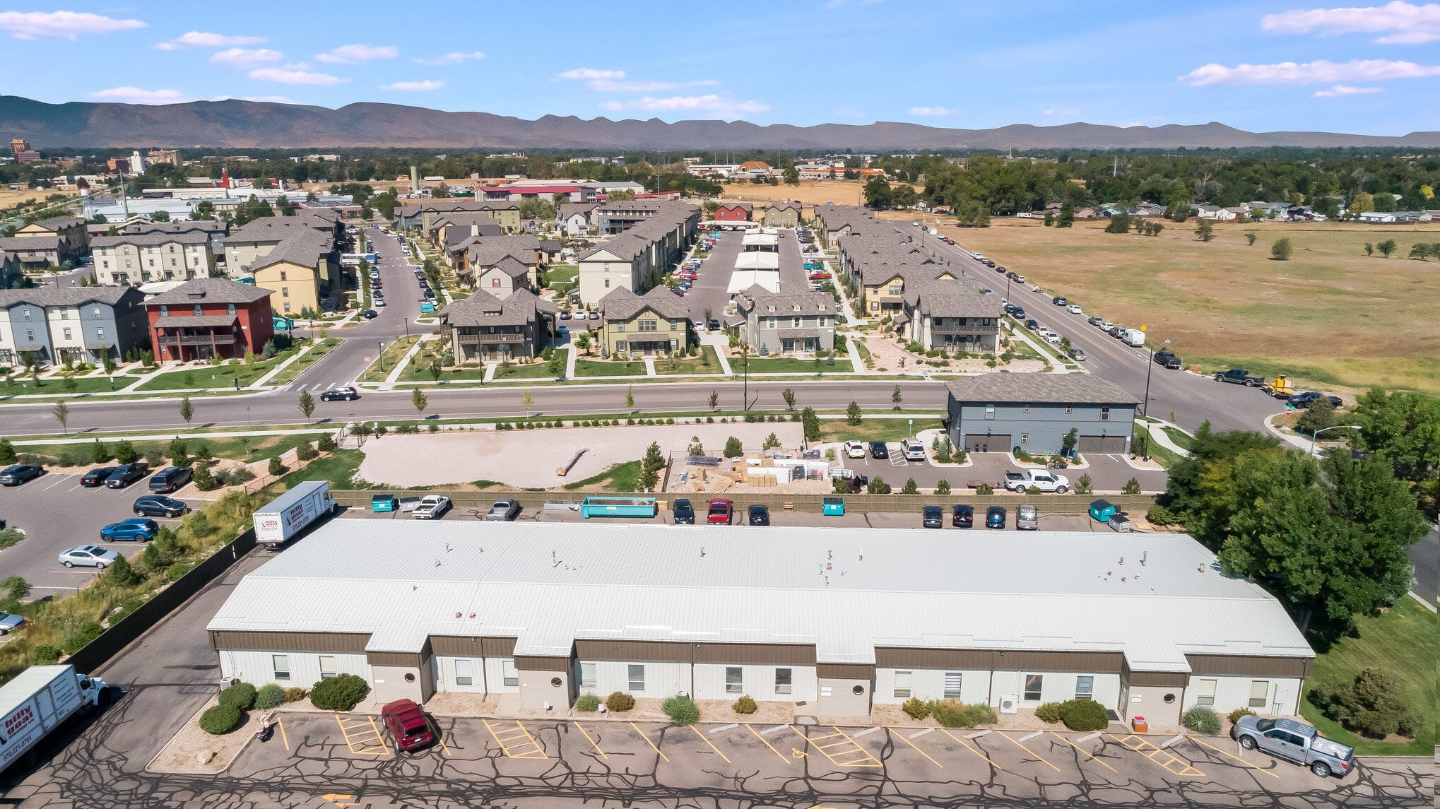 Aerial view showing the outside of a commercial building in a neighborhood next to the foothills