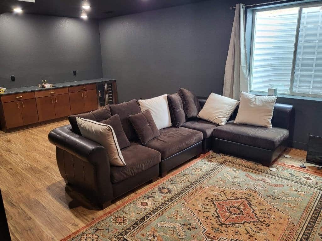 Family room with sectional sofa, dark gray walls, and wet bar