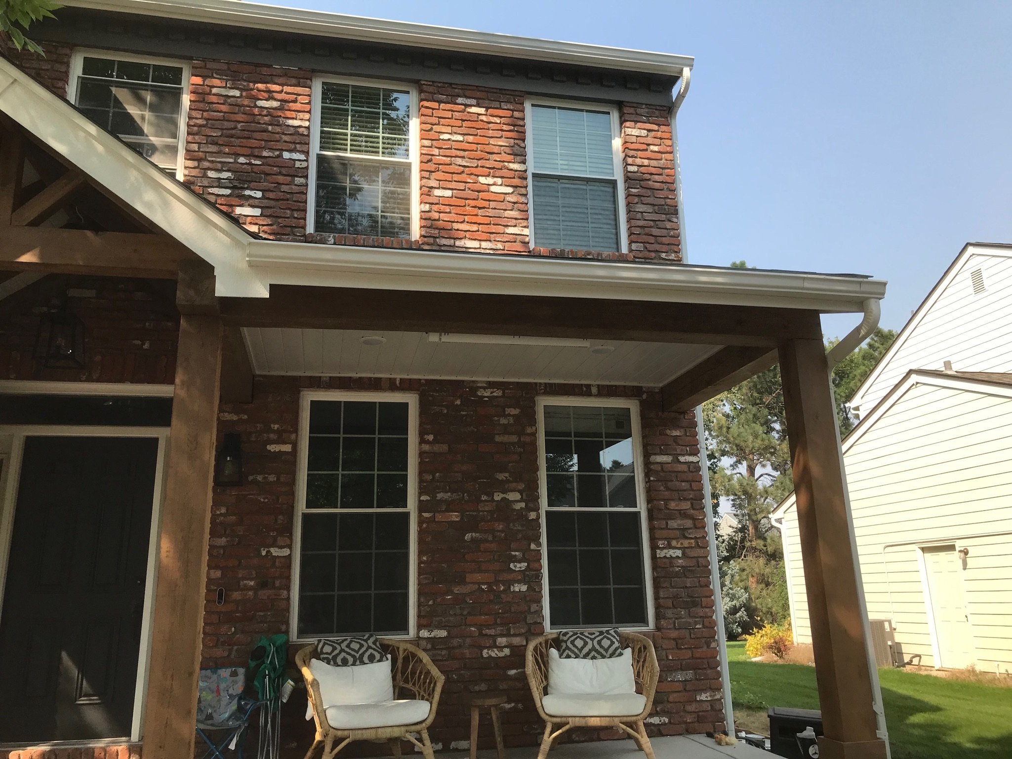 Outdoor view of a brick home with front porch and chairs