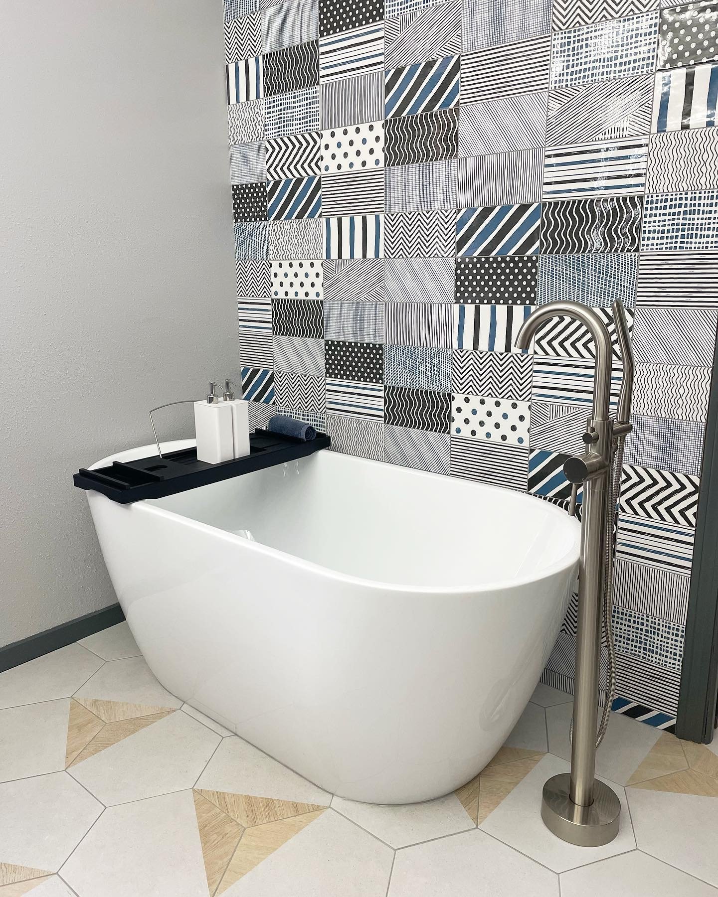 Large soaking tub next to funky geometric tile wall