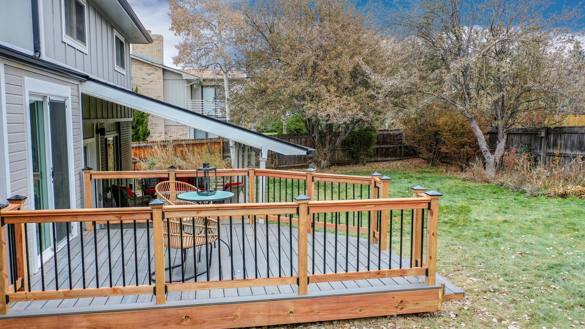 Outdoor deck with wood and metal railing in a fenced-in back yard