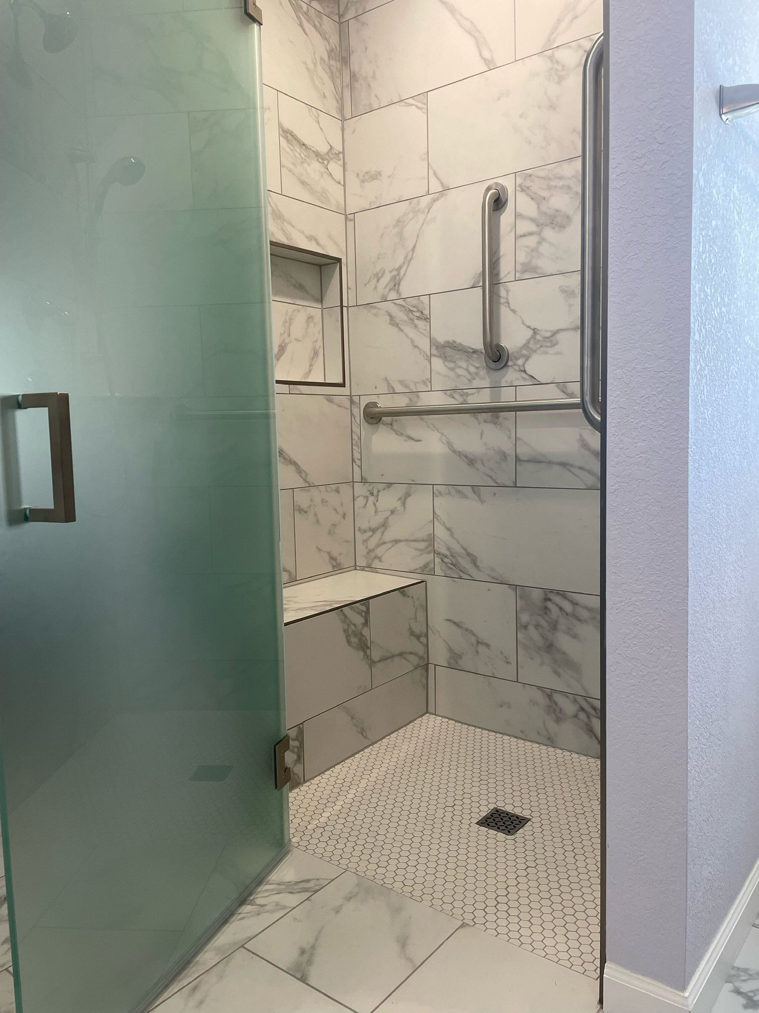 Walk-in shower with marble tile and glass door