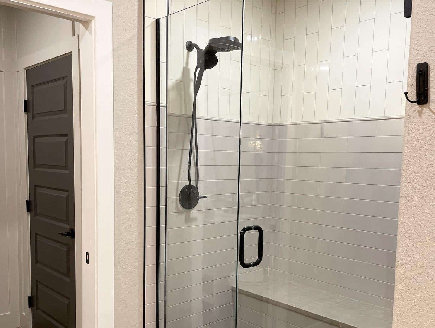 Walk-in shower with black shower head and white and gray tiles
