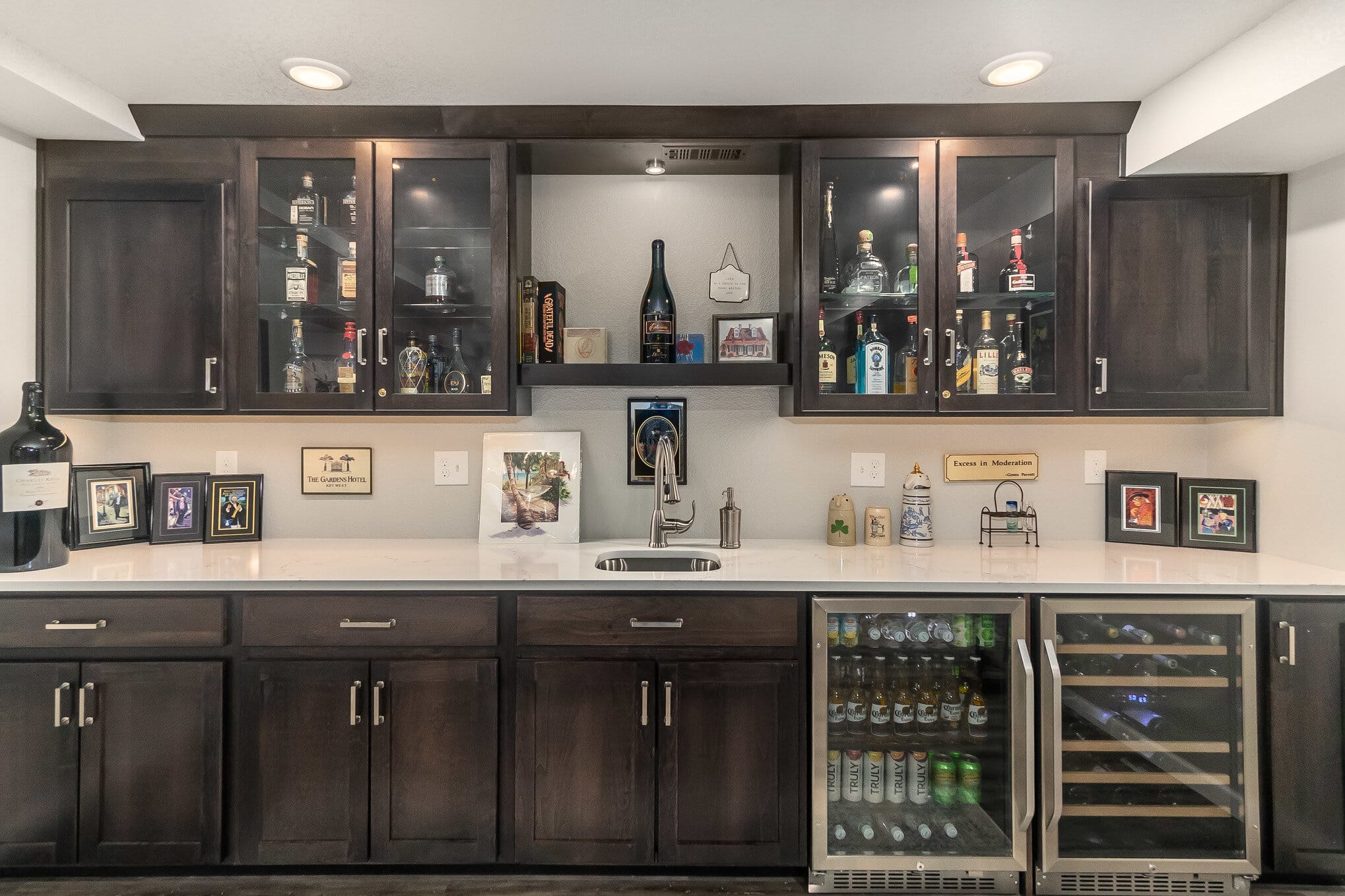 Game room wet bar with dark wood cabinets and white counter top