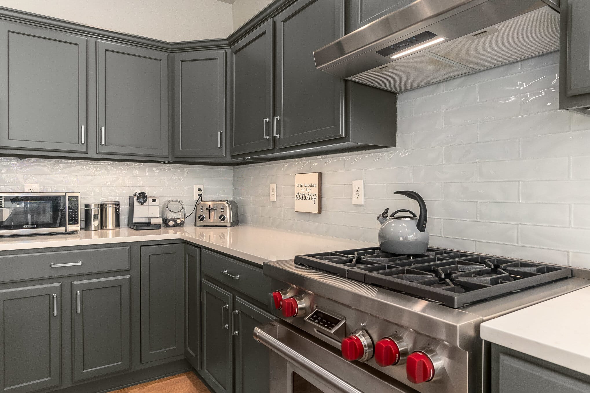 Gray kitchen cabinets with white countertops and professional gas stove
