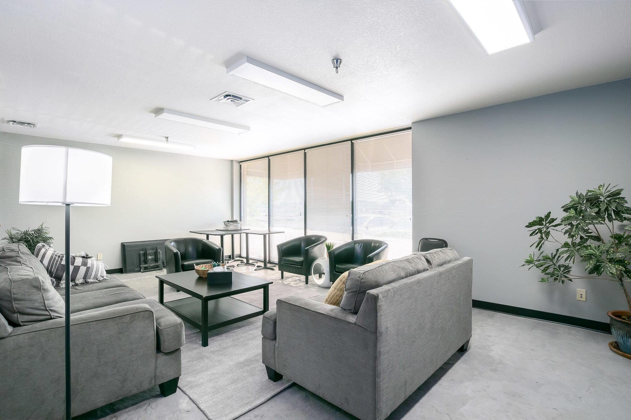 Stylish waiting room with gray couches and black leather chairs