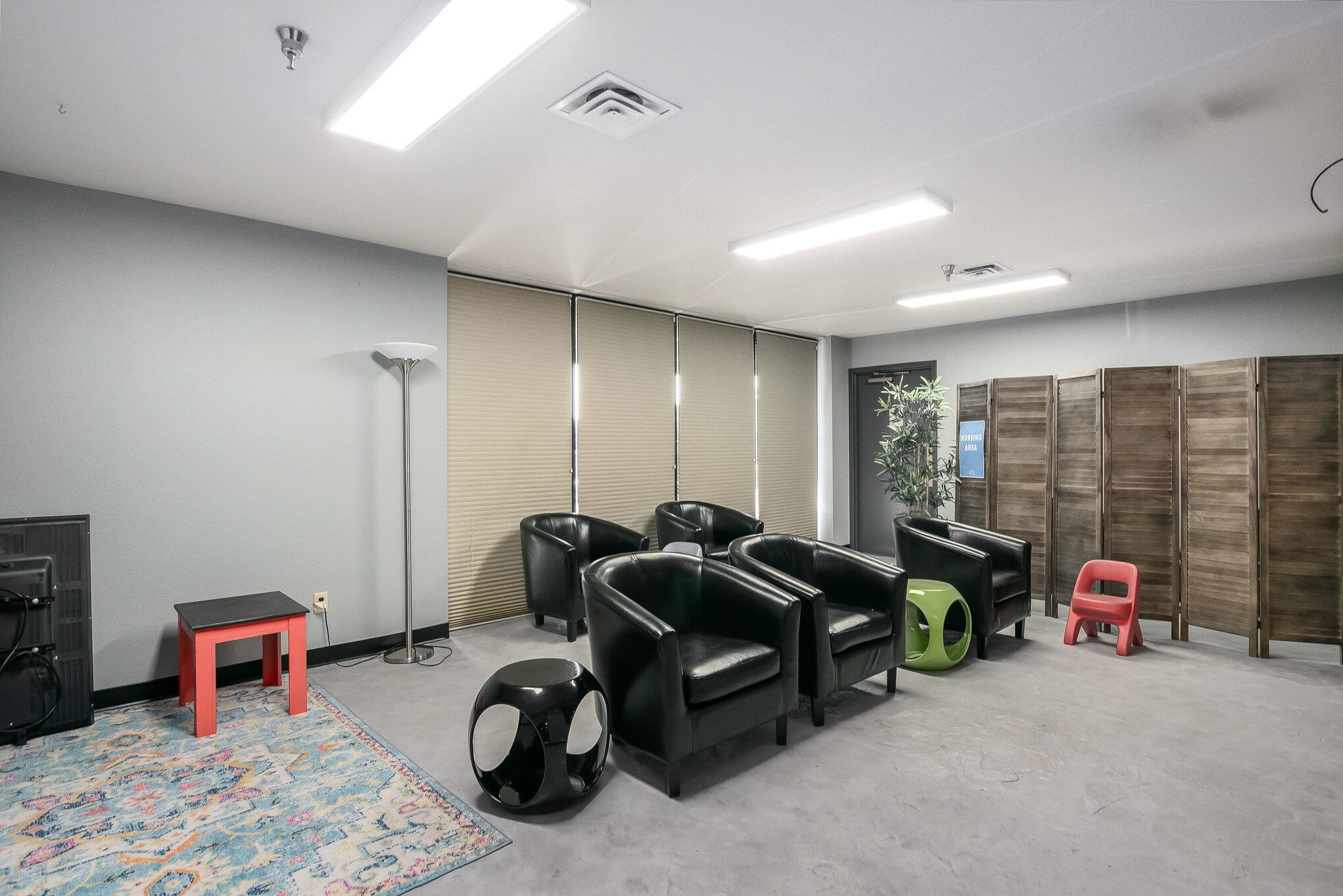 Indoor commercial space with black leather armchairs and funky metal side tables in green and black