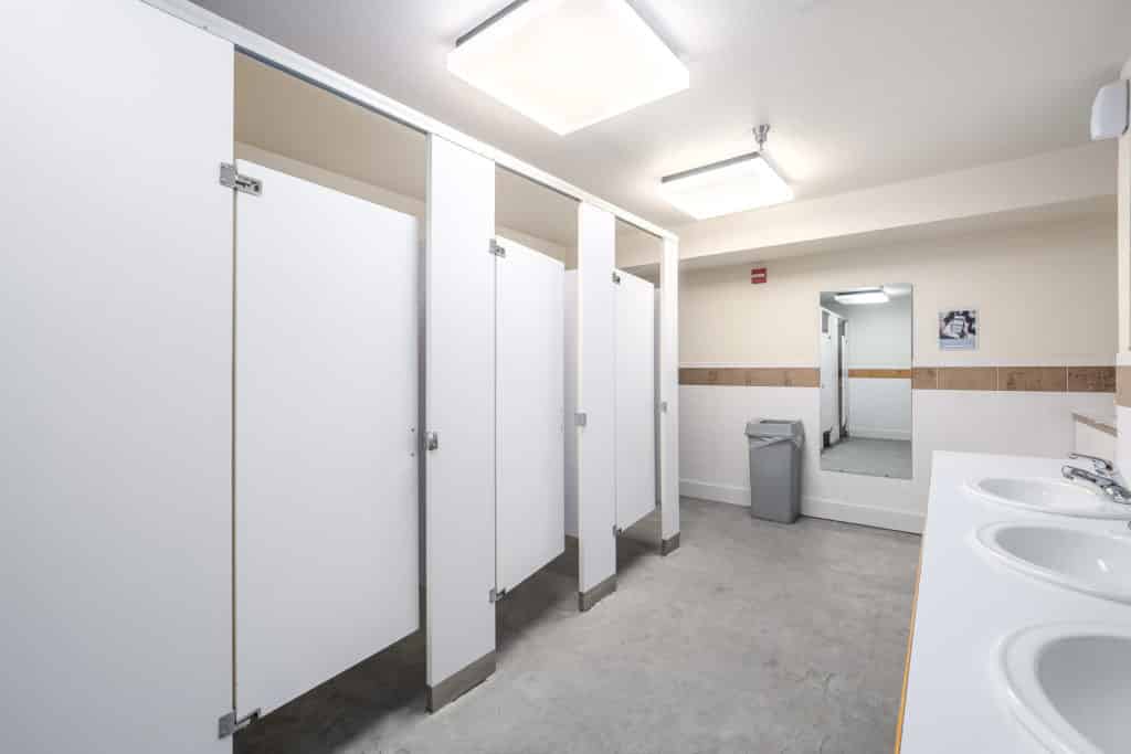 Public restroom with three white stalls and gray floor