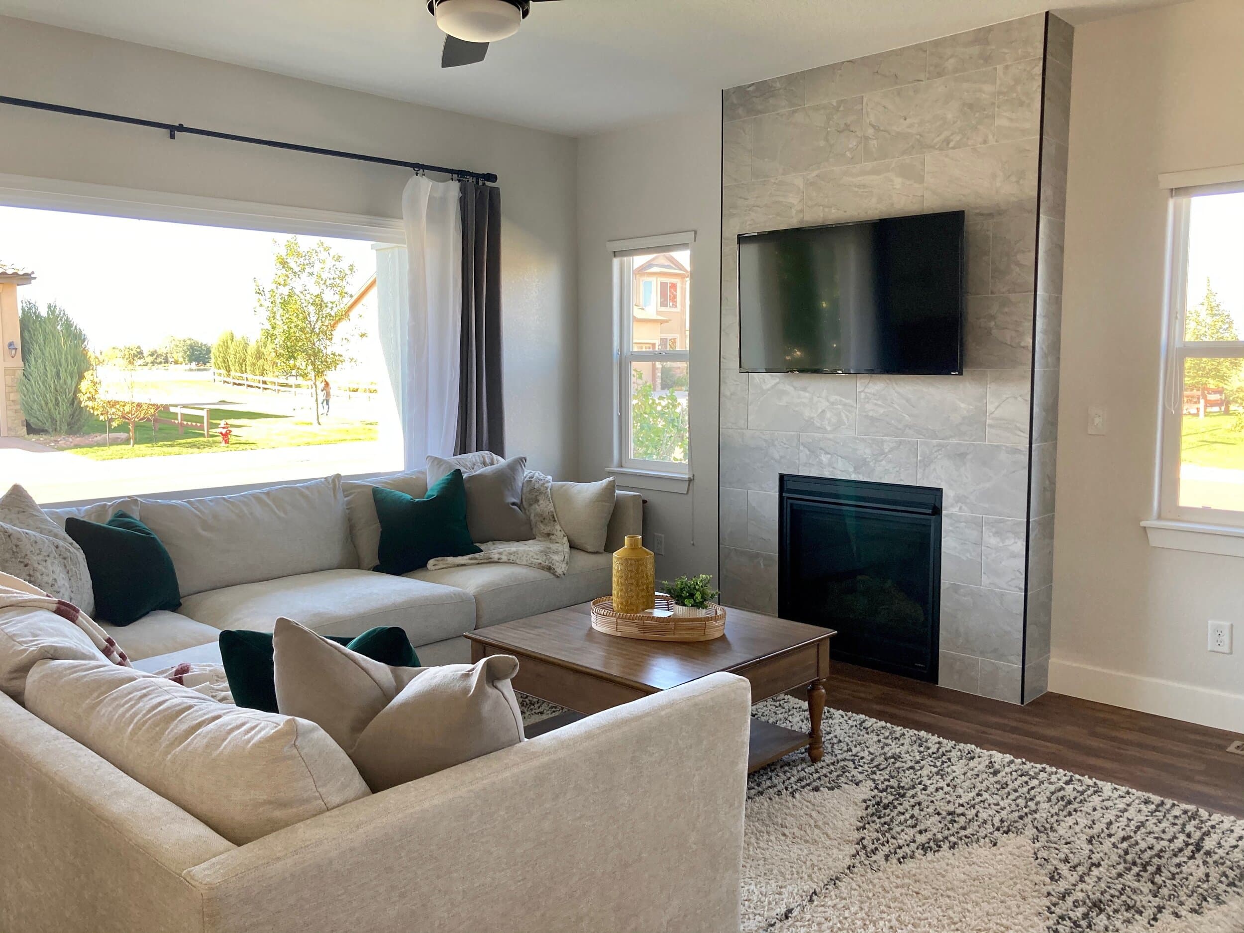 Family room with light gray sectional couch and large tile fireplace