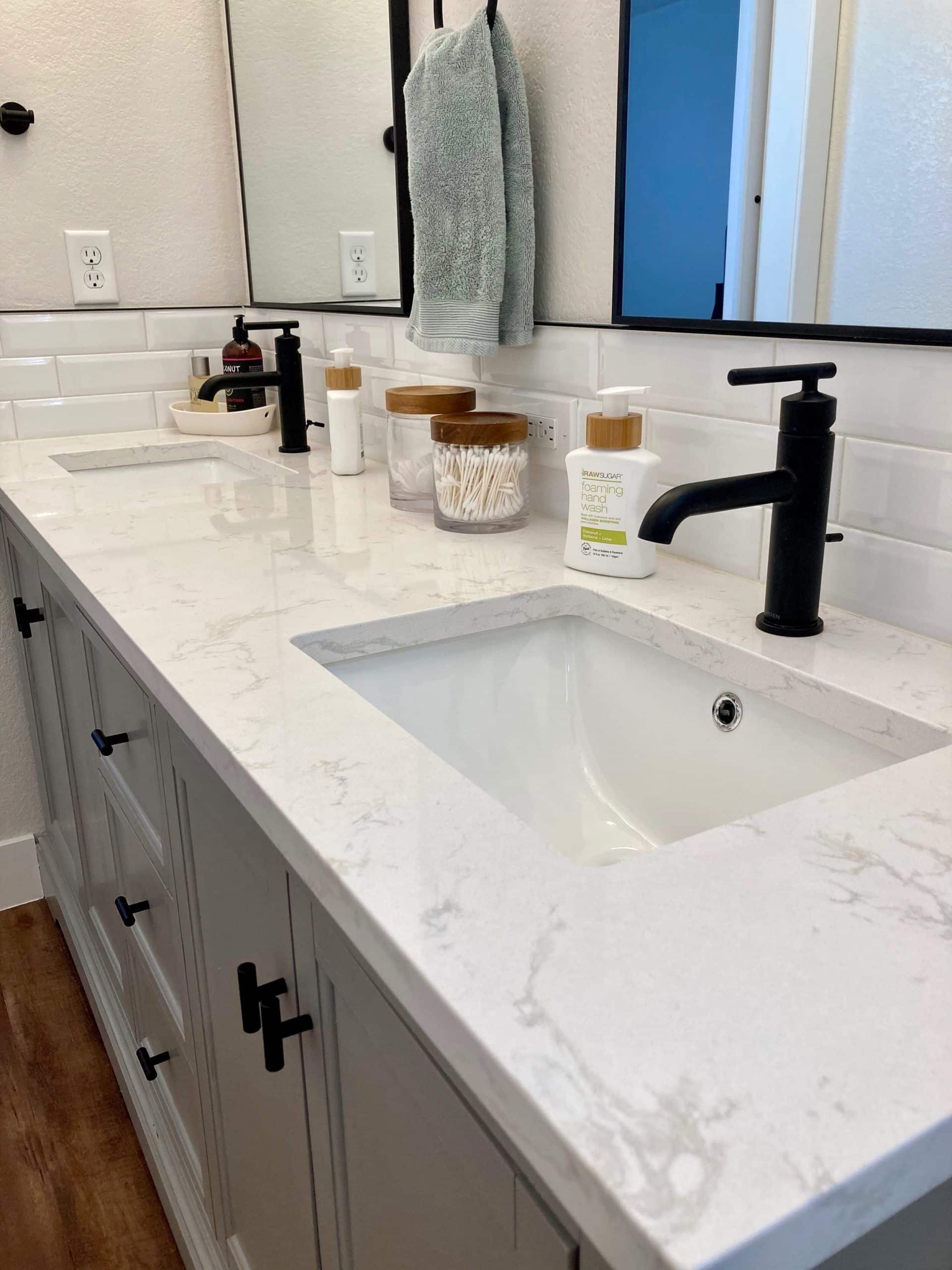Close-up of a double bathroom vanity with white marble counters and black faucets