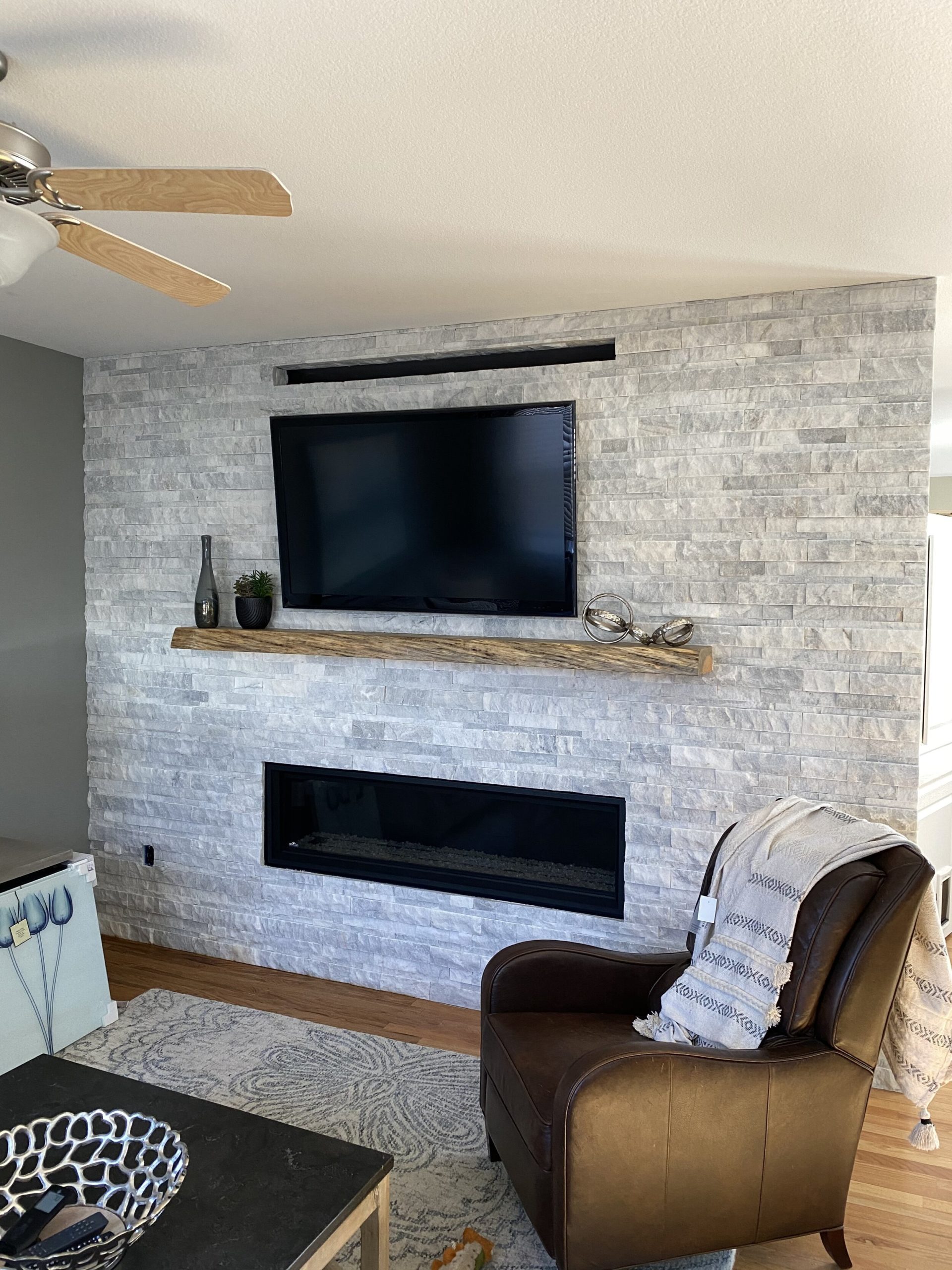 Large white stone fireplace with wooden mantel and mounted TV