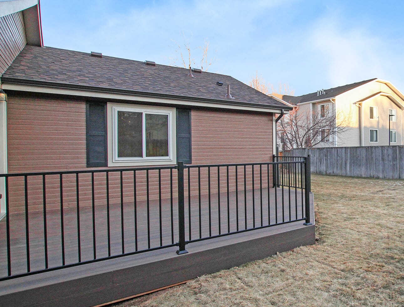 Back deck attached to home with brown siding and white window trim