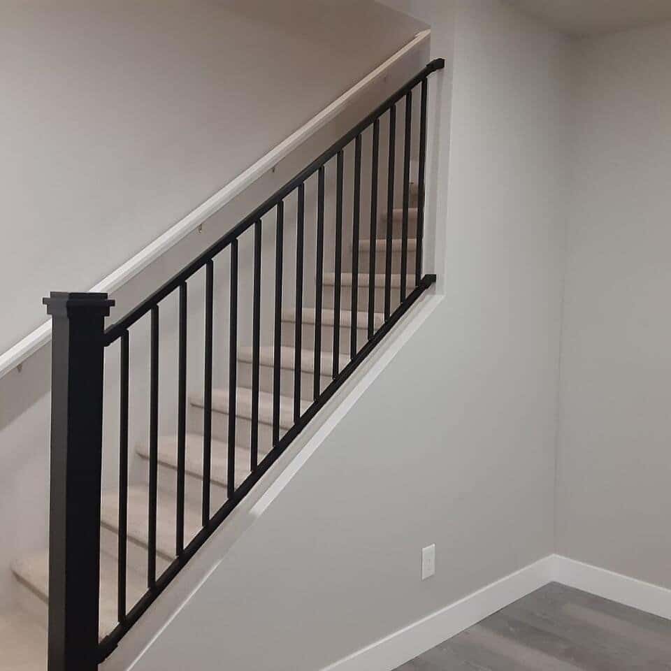 Staircase with light carpet and black hand rail