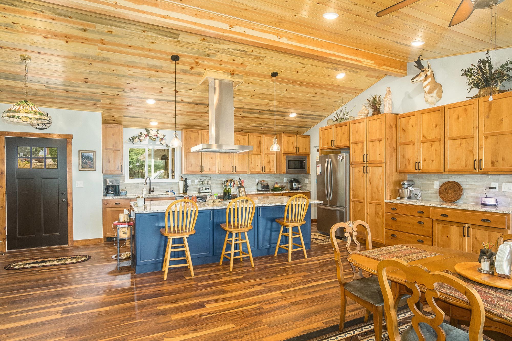 Rustic style dining room and kitchen with wooden cabinets and ceiling